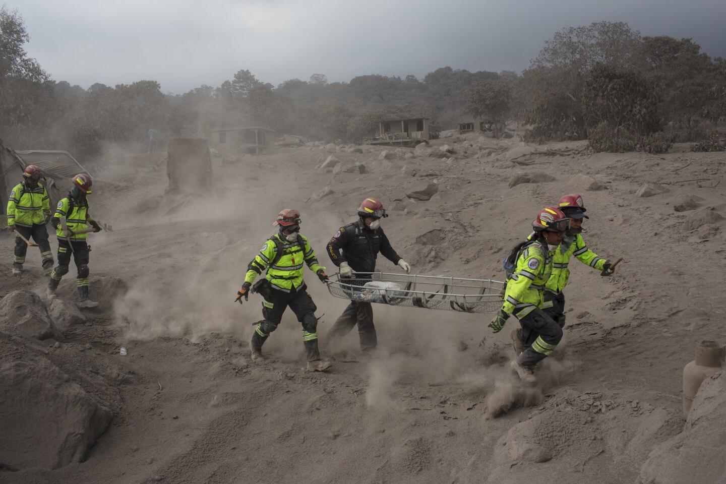 Rescue workers run for cover as the Fuego volcano in Guatemala blows more clouds of ash in the El Rodeo hamlet of Escuintla, Guatemala.