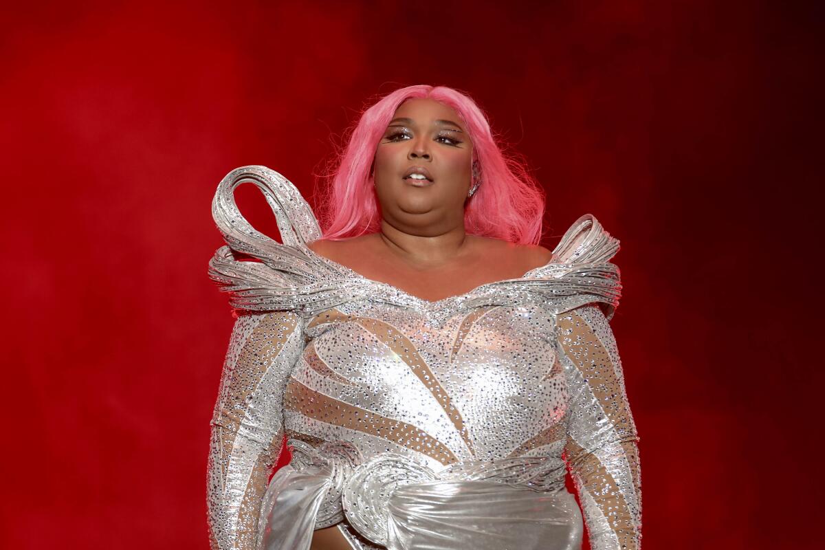 Lizzo wears a sliver leotard with exaggerated shoulders as she performs onstage
