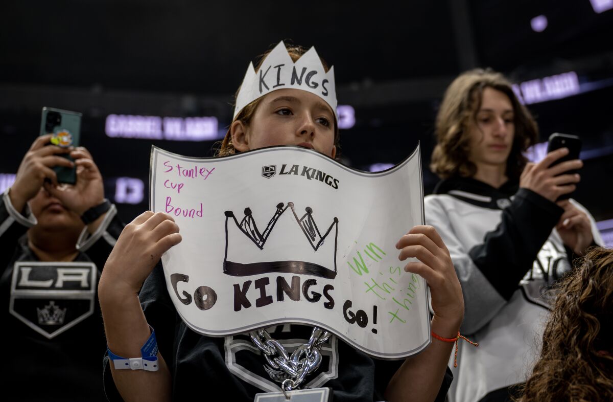 A young Kings fan wears a paper crown while holding a sign during Game 6 warmups.