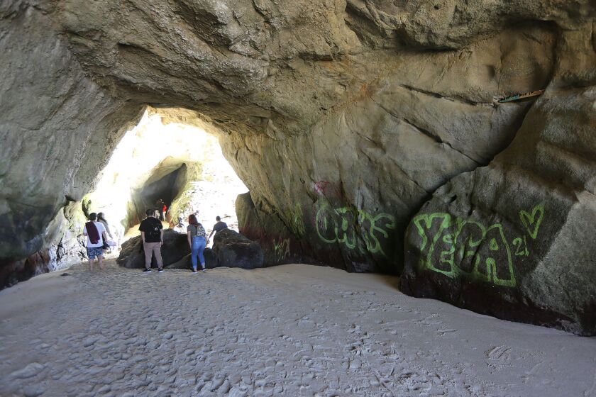 Beach-goers explore and take pictures in a sea cave at 1,000 Steps Beach in south Laguna. The cave was recently "tagged" by spray paint angering locals.