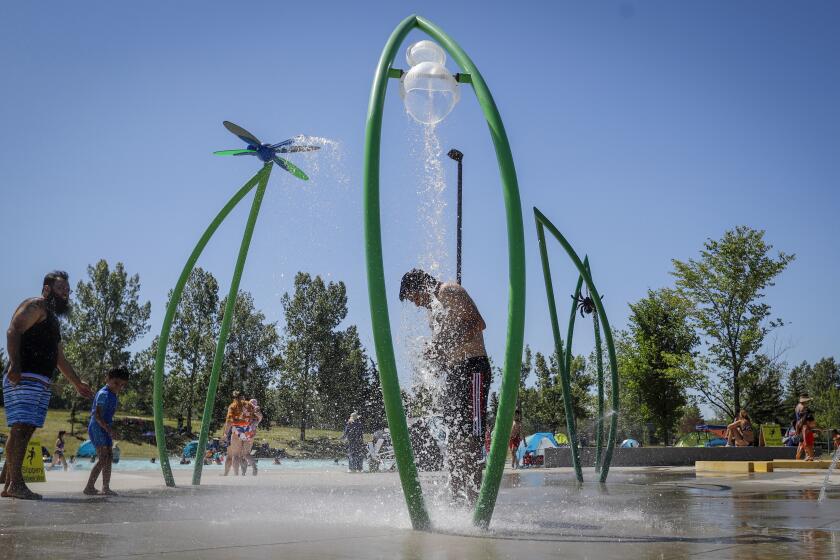 FILE - In this Wednesday, June 30, 2021 file photo, a man stands under a water feature trying to beat the heat at a splash park in Calgary, Alberta. Scientists say there’s something different this year from the recent drumbeat of climate weirdness. This summer a lot of the places hit by weather disasters are not used to getting extremes and many of them are wealthier, which is different from the normal climate change victims. That includes unprecedented deadly flooding in Germany and Belgium, 116-degree heat records in Portland, Oregon and similar blistering temperatures in Canada, along with wildfires. Now Southern Europe is seeing scorching temperatures and out-of-control blazes too. And the summer of extremes is only getting started. Peak Atlantic hurricane and wildfire seasons in the United States are knocking at the door. (Jeff McIntosh/The Canadian Press via AP, FIle)