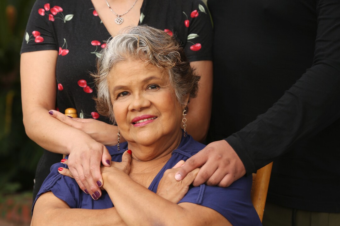 Maria Guadalupe “Lupita” Olague holds the hands of her children, Luz and Raul Arango, at their home in Pico Rivera.