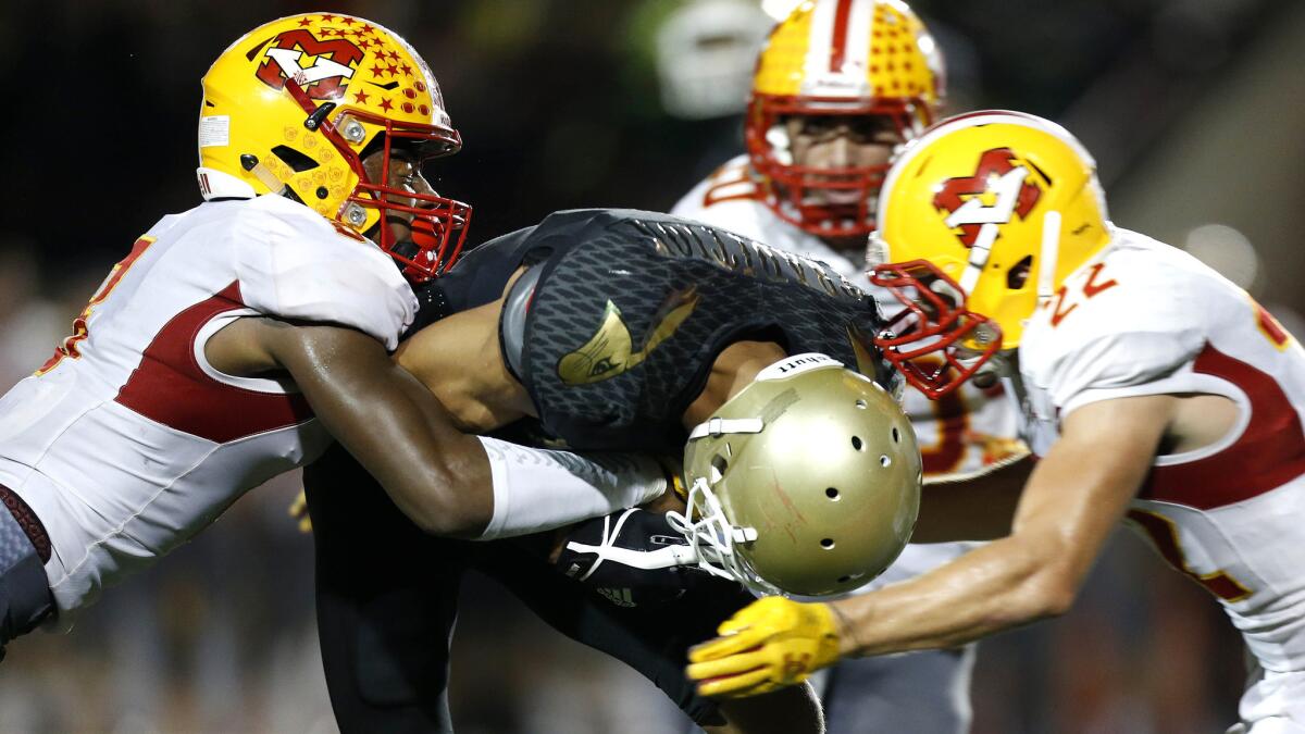 Poly wide receiver Jalen Hall is brought down by Mission Viejo defenders Chris Mitchell, left, and Ryan Kennedy on Friday night.