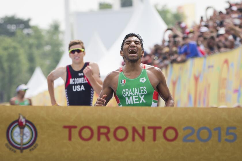 El mexicano Crisanto Grajales (der) reacciona al cruzar la meta para ganar la medalla de oro sobre el estadounidense Kevin McDowell en el triatlón masculino de los Juegos Panamericanos en Toronto.