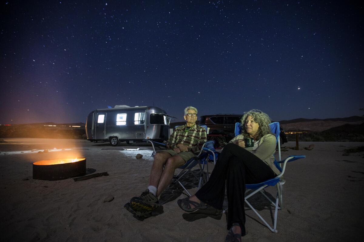 Charles and Julie Fleming check out the stars on a clear night by a campfire at dusk while camping in an Airstream Bambi Sport at Red Rock Canyon Ricardo campground. (Allen J. Schaben / Los Angeles Times)