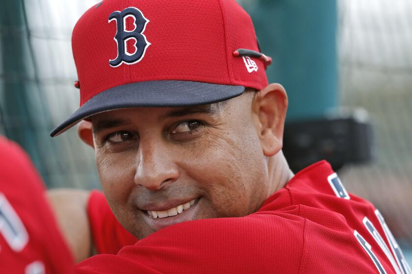 FILE - In this Feb. 18, 2019, file photo, Boston Red Sox manager Alex Cora smiles from behind the batting cage during their first full squad workout at their spring training baseball facility in Ft. Myers, Fla. The Red Sox rehired Cora as manager Friday, Nov. 6, 2020, less than a year after letting him go because of his role in the Houston Astros cheating scandal. (AP Photo/Gerald Herbert, File)