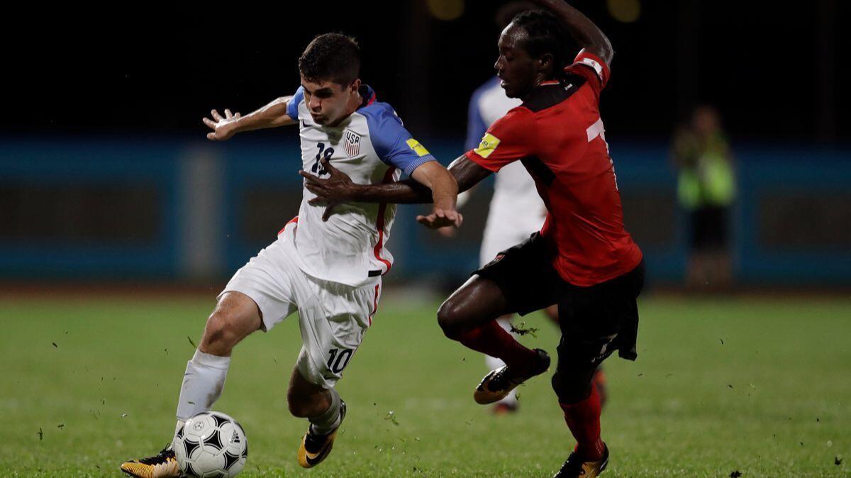 United States' Christian Pulisic, left, fights for the ball with Trinidad and Tobago's Nathan Lewis during a 2018 World Cup qualifying soccer match in Couva, Trinidad.