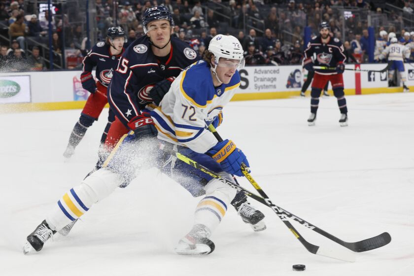 Buffalo Sabres' Tage Thompson, right, keeps the puck away from Columbus Blue Jackets' Gavin Bayreuther during the third period of an NHL hockey game Wednesday, Dec. 7, 2022, in Columbus, Ohio. (AP Photo/Jay LaPrete)