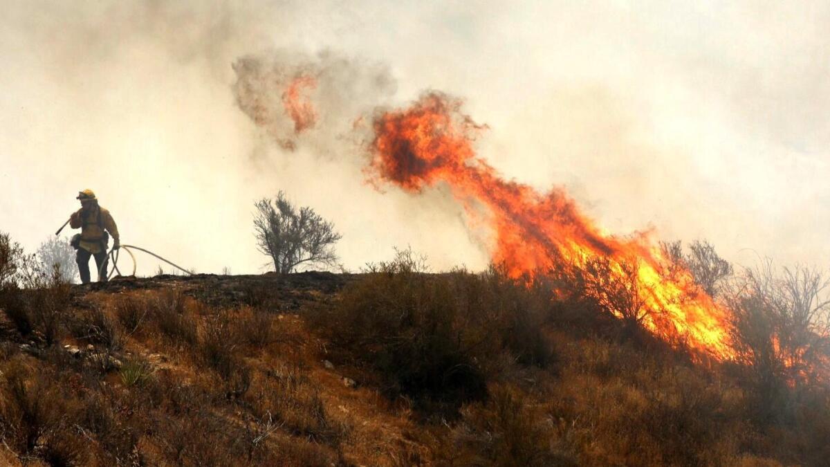 Fire flares up in brush along Soledad Canyon Road near Acton on Monday.