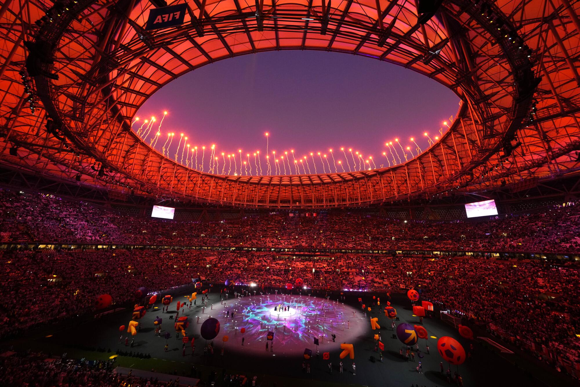 Fireworks explode above a red-lighted stadium as artists perform during the World Cup closing ceremony.