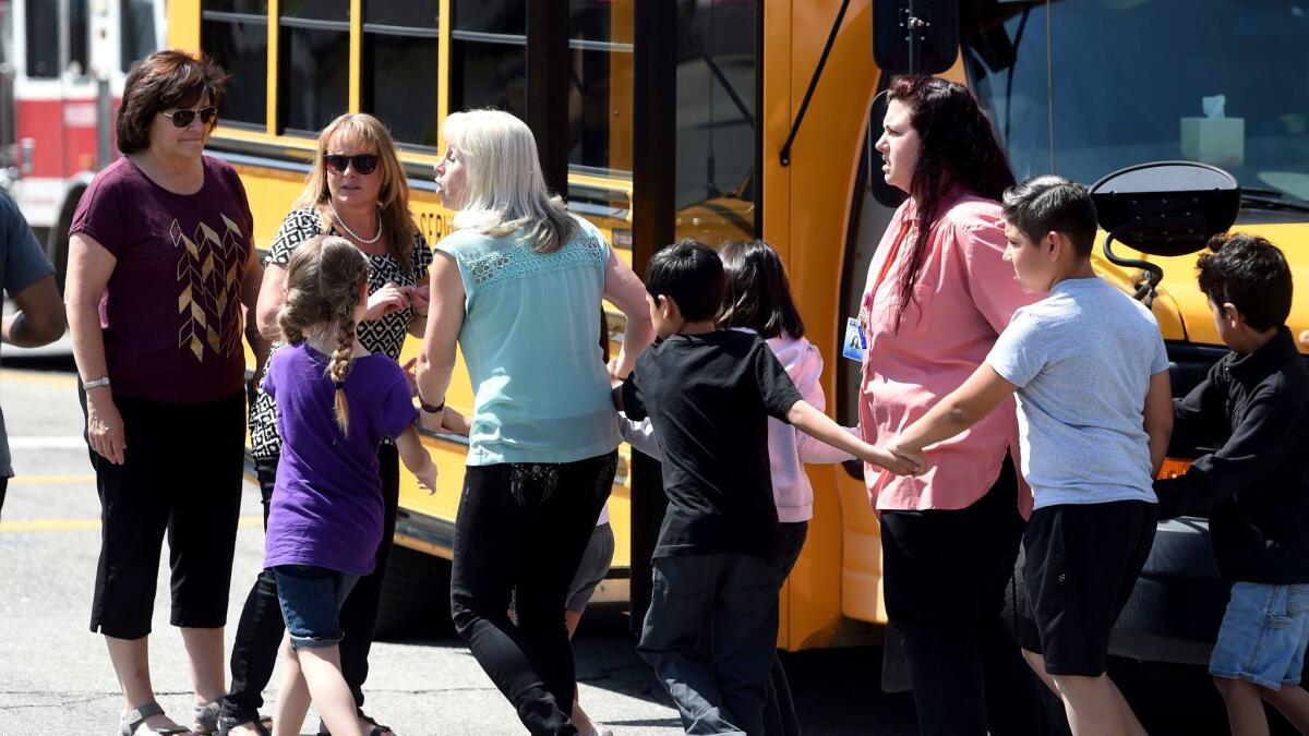 North Park Elementary teaching assistant Jennifer Downing, right, evacuates the building in San Bernardino with students after a shooting April 10.