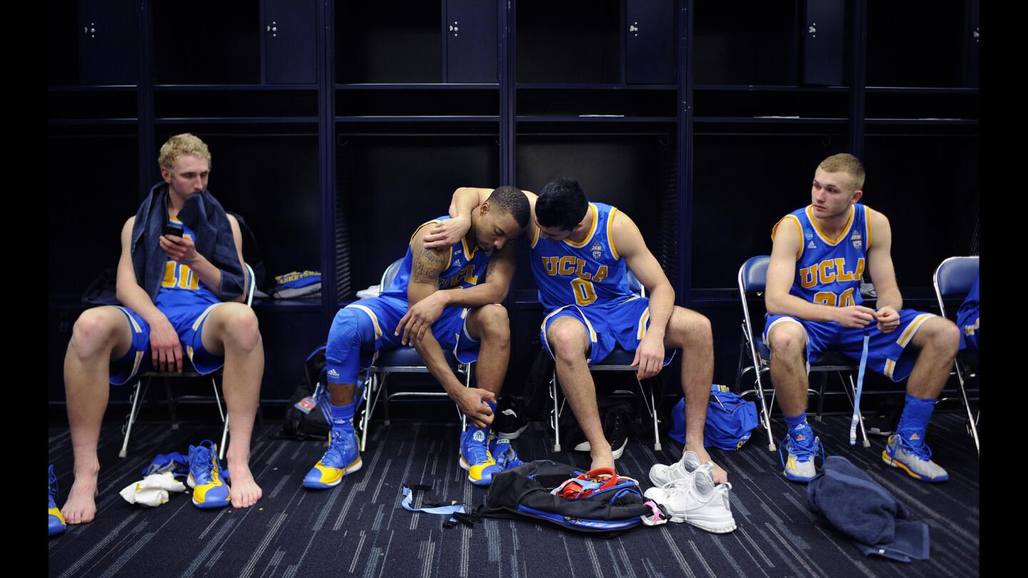 UCLA guard Norman Powell is consoled by Nick Kazemi as teammates Thomas Welch, left, and Bryce Alford join them in the locker room following the South Regional semifinal loss to Gonzaga.
