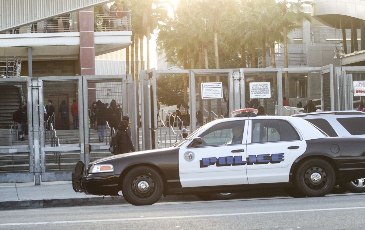 A police vehicle patrols by a school in Los Angeles on Dec. 16 after the L.A. Unified School District received an email threat that shut down schools for a day. In Long Beach on Thursday, the school district received a similar threat but is remaining open.