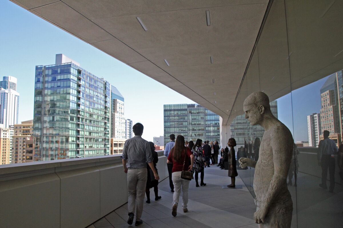 A sculpture of a male figure can be seen in the foreground of a terrace, with city views in the background.