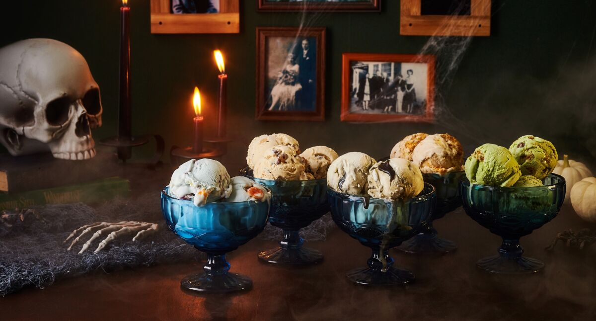 A fake skull and skeleton hand sit next to bowls of ice cream.