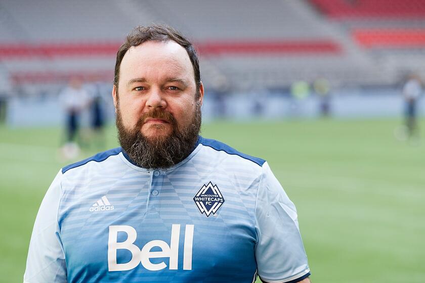 Actor Chris Gauthier poses for a photo in a blue soccer jersey on a soccer field