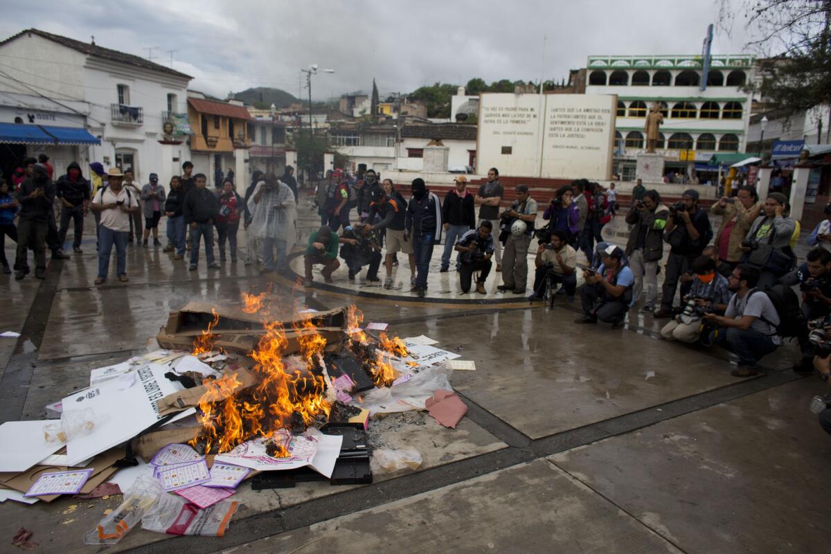 Journalists take pictures as ballots and other election materials burn in the main square of Tixtla, Mexico, during a protest on June 7.