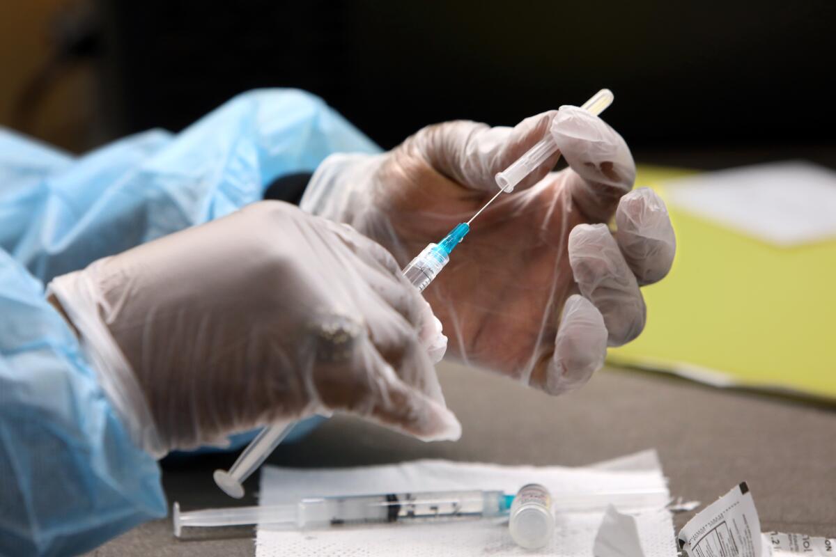 A nurse prepares a syringe of COVID-19 vaccine.