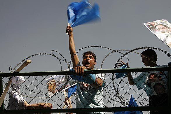 A supporter of Abdullah Abdullah scales a fence at the campaign rally.