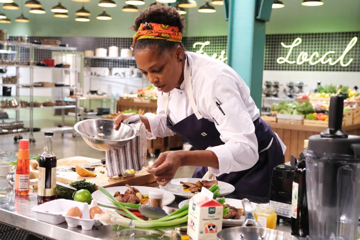 A woman plating food in a professional kitchen