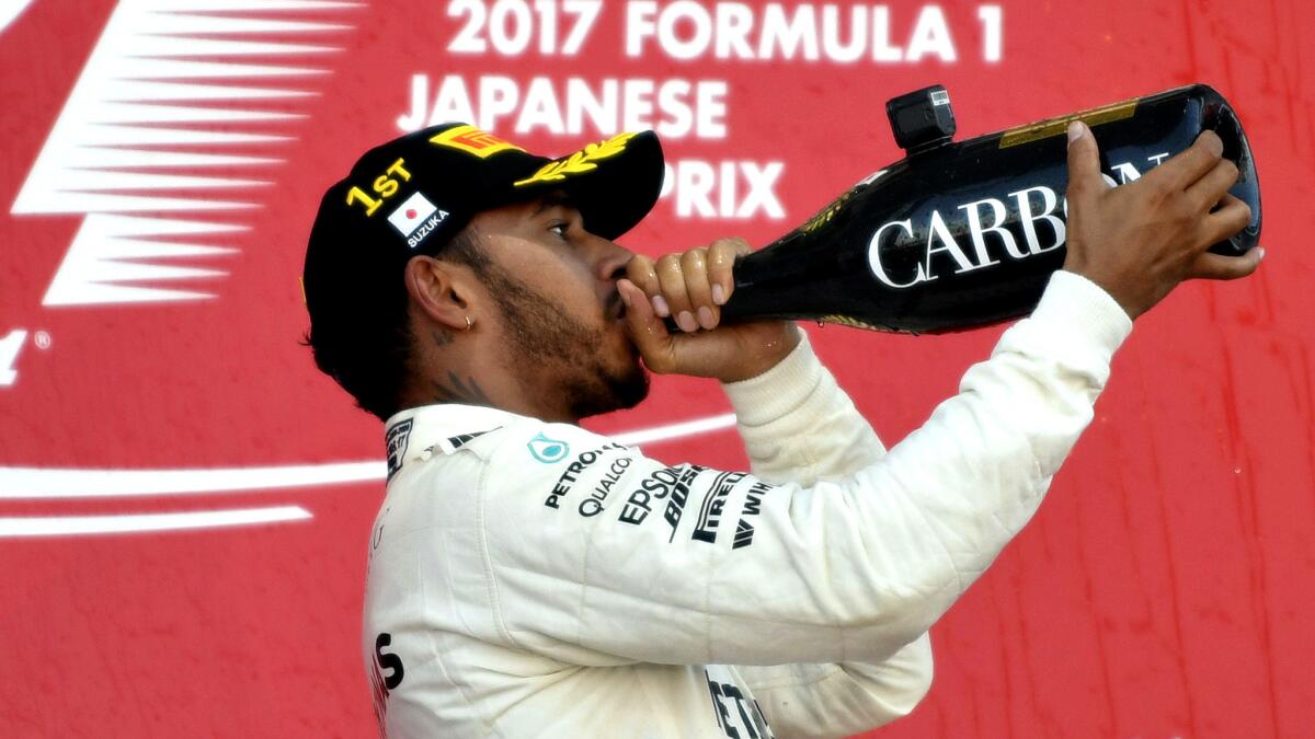 Formula One driver Lewis Hamilton celebrates on the podium after winning the Japanese Grand Prix on Sunday.