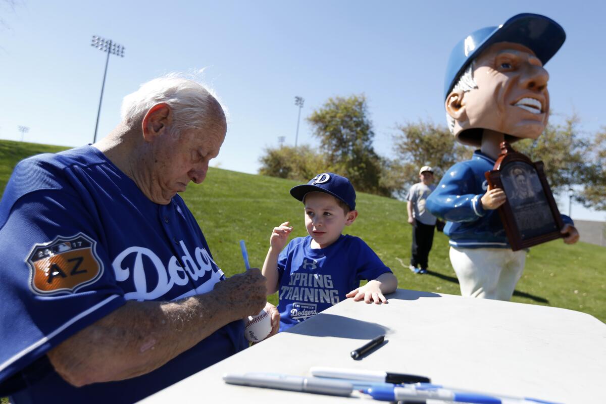 Tommy Lasorda signs an autograph for Drake Colley, 5, at Dodgers spring training in February 2017.