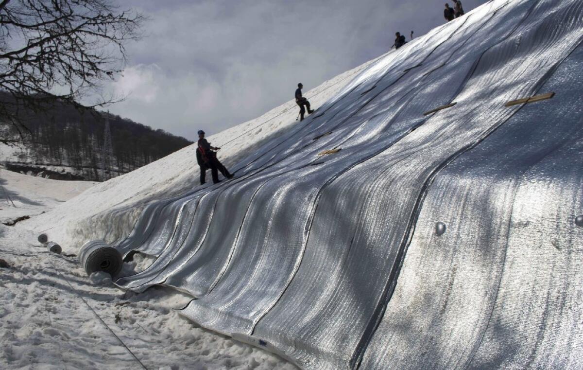 Workers cover a hill of snow outside Sochi, Russia, with protective blankets in April. Some 450,000 cubic meters of last year's snowfall have been stored if needed for the 2014 Winter Olympics.