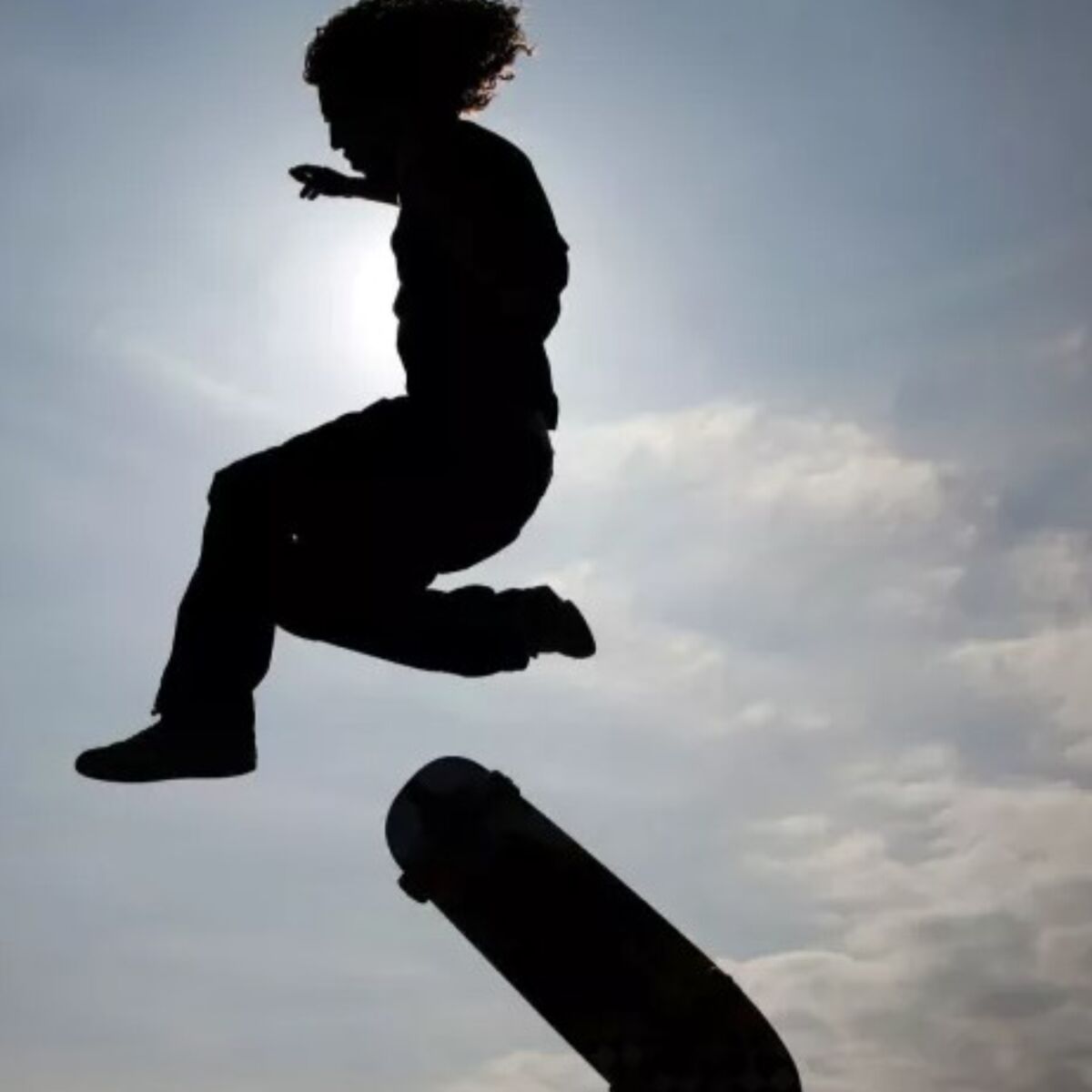 A boy jumps off his skateboard.