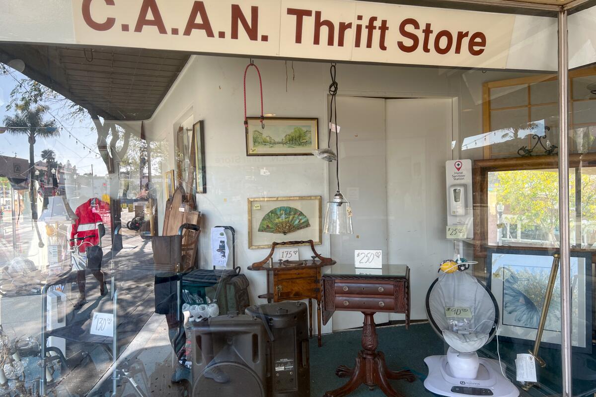 The front window case of the C.A.A.N. Thrift Store displays furniture and framed artwork.