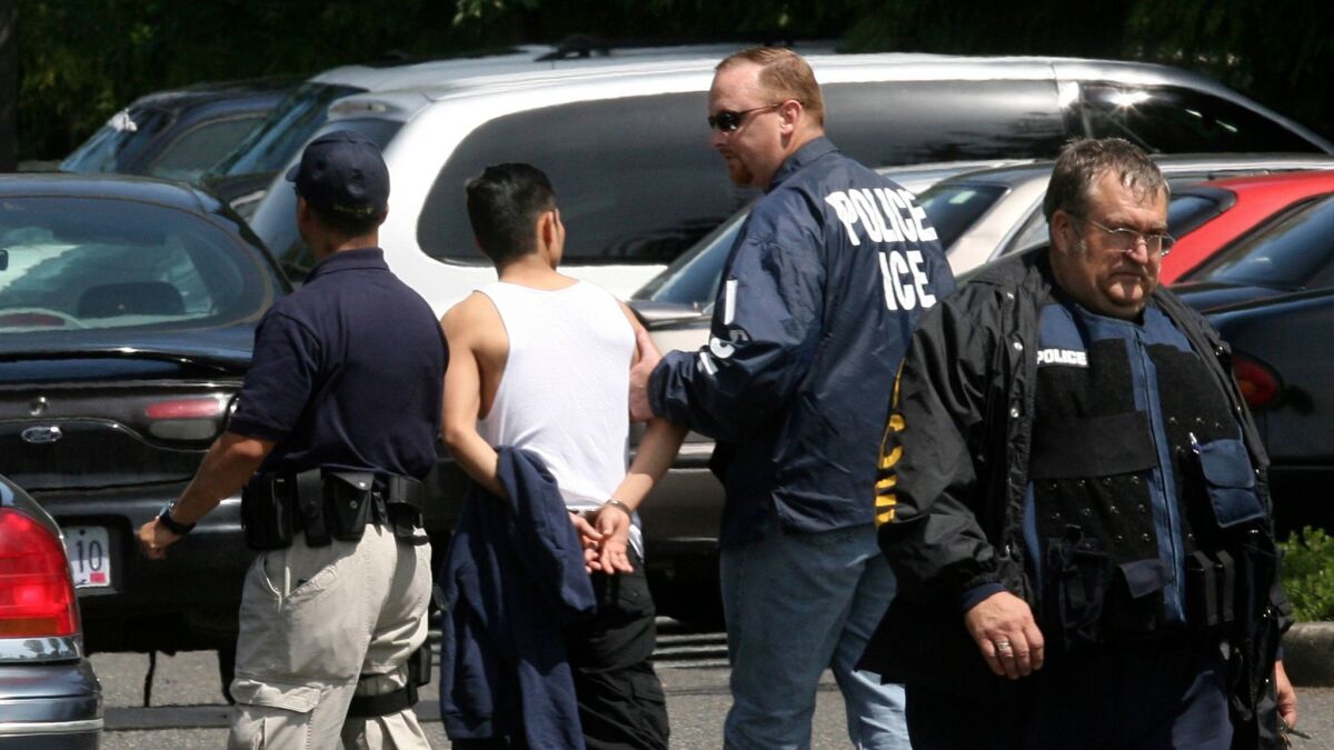Federal immigration agents walk a man in handcuffs on June 12, 2007, in Portland, Ore.