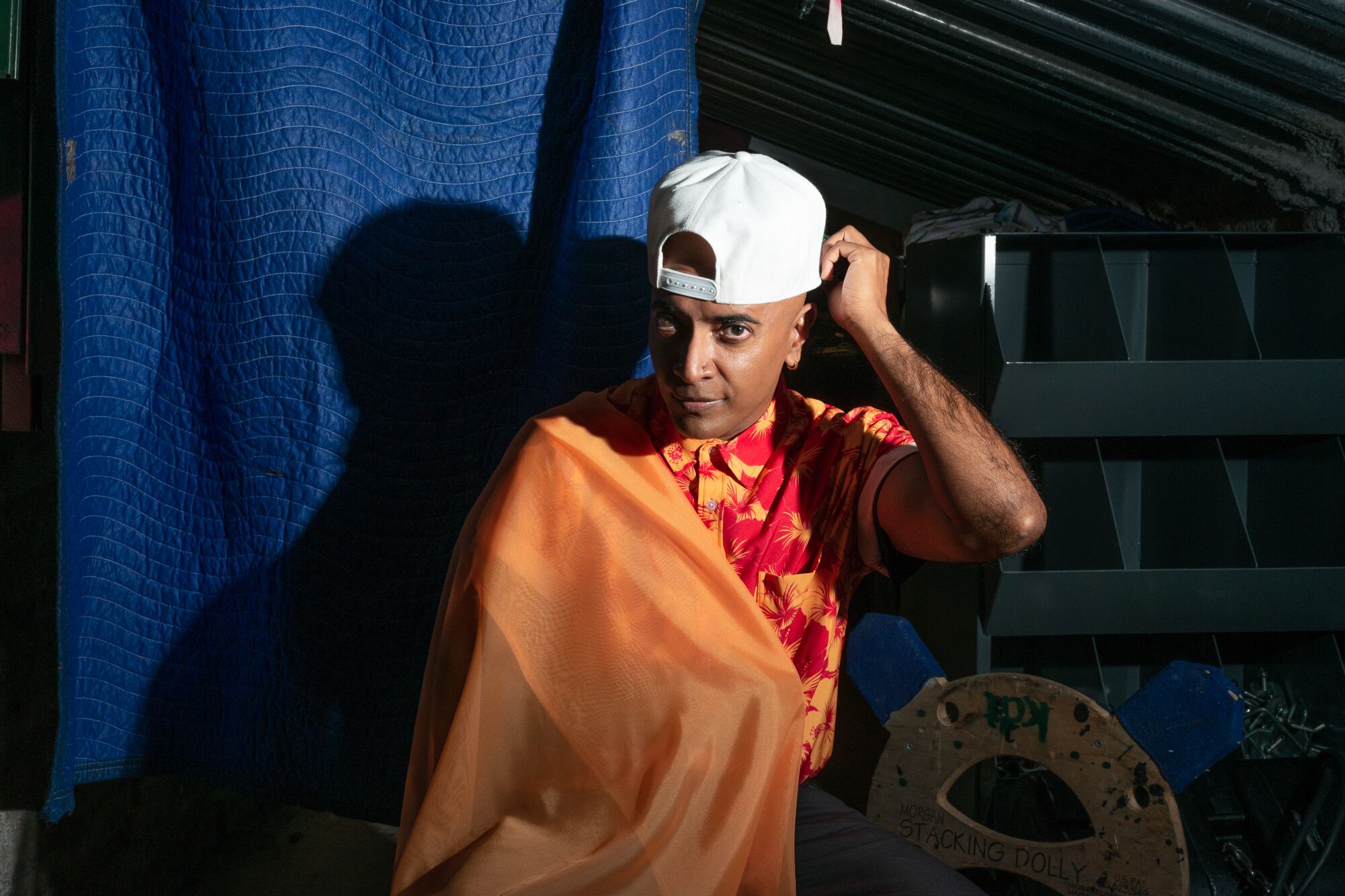 A man in an orange shirt and a backward white ballcap.