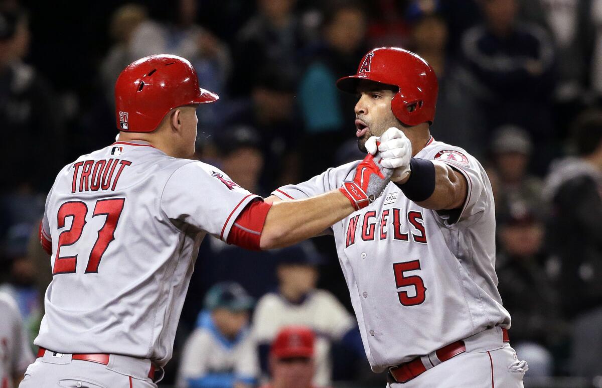 Albert Pujols (5) is greeted at home by Mike Trout (27) after Pujols' three-run home run against the Mariners during the ninth inning of a game on May 14.