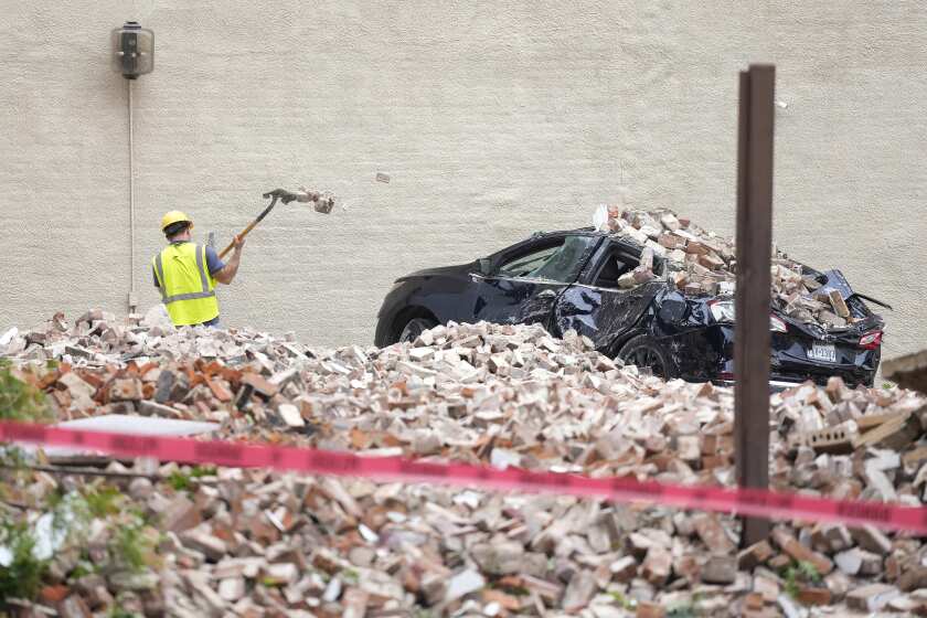 A worker digs out bricks from a collapsed wall near Commerce and Main Street downtown on Friday, May 17, 2024, in Houston, after a strong thunderstorm moved through Thursday evening. (Karen Warren/Houston Chronicle via AP)