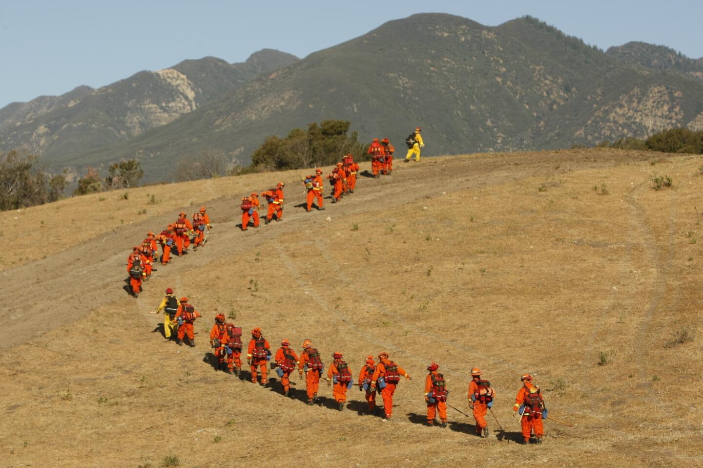 A firefighting hand crew marches into the hills as they mop up after the Fillmore fire in Ventura County, which was sparked Monday by a downed power line.