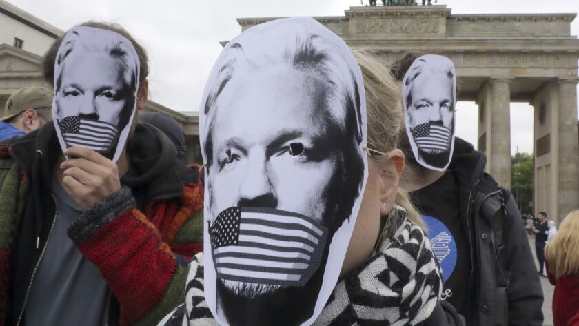 People wear paper masks to protest against a possible extradition of WikiLeaks founder Julian Assange to the U.S. in front of the Brandenburg Gate in Berlin on Thursday.