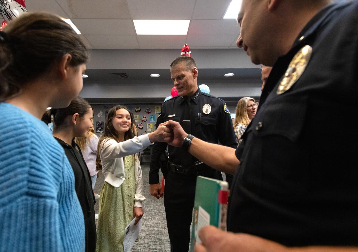 Huntington Beach Police Lt. Julio Mendez, right, and Chief Eric Parra greet students.