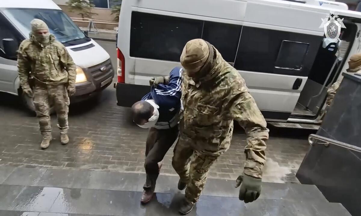 A blindfolded suspect is led to the Russian Investigative Committee headquarters in Moscow.