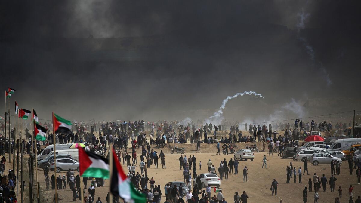 Black smoke from burning tires hovers over Palestinian protesters during clashes with Israeli troops near the border.