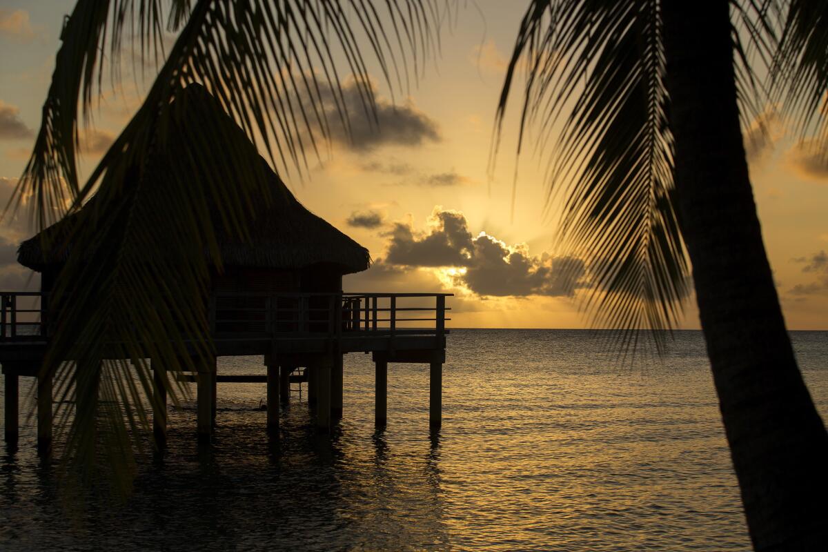 The sun sets behind Hotel Kia Ora’s overwater bungalows. Each of these rooms has a deck with direct lagoon access for snorkeling.