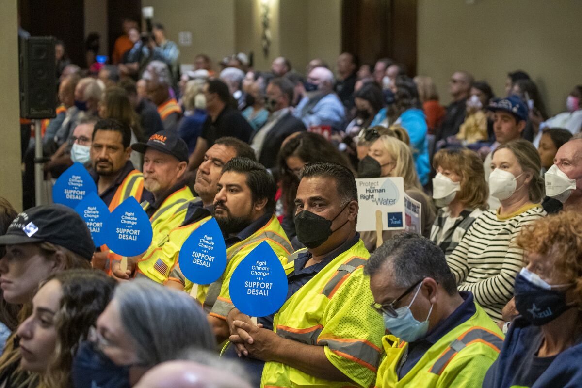 Union workers who support Poseidon Water desalination project hold signs of support at California Coastal Commission hearing