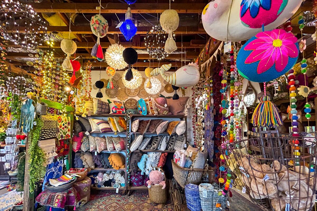 The interior of a shop filled with colorful pillows, objects and plants