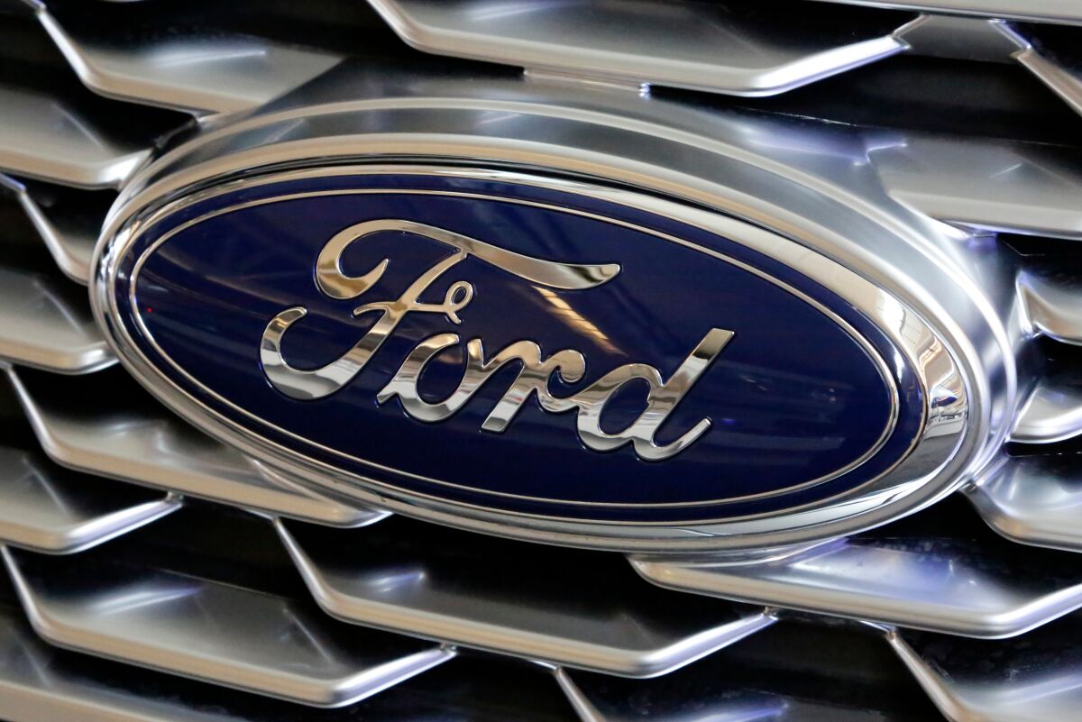 FILE- This Feb. 15, 2018, file photo shows a Ford logo on the grill of a 2018 Ford Explorer on display at the Pittsburgh Auto Show. Ford Motor Co. will offer early retirement incentives with hopes of cutting its U.S. white-collar workforce by 1,400 more positions. President for the Americas Kumar Galhotra told employees about the offers Wednesday, Sept. 2, 2020. (AP Photo/Gene J. Puskar, File)