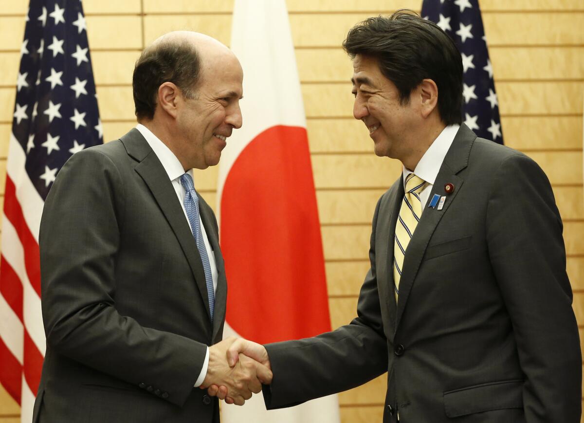 Japanese Prime Minister Shinzo Abe, right, shakes hands with U.S. Ambassador to Japan John Roos in Tokyo on Friday at their joint announcement of the Okinawa plan.
