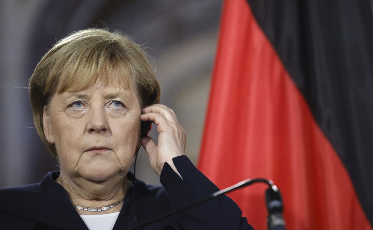 German Chancellor Angela Merkel adjusts her earpiece as she participates in a media conference with Belgium's Prime Minister Alexander De Croo at the Egmont Palace in Brussels, Friday, Oct. 15, 2021. (AP Photo/Olivier Matthys)
