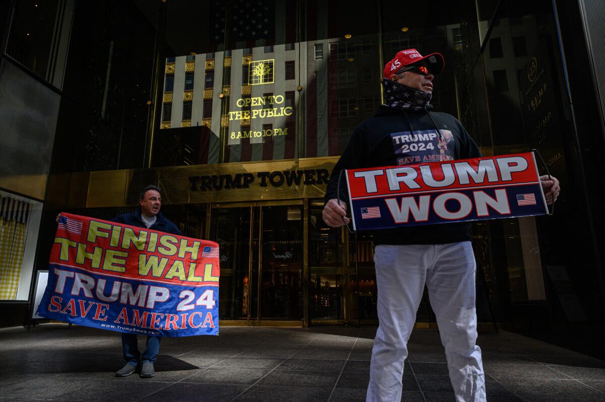 Two people hold signs reading "Trump Won" and "Finish the Wall."