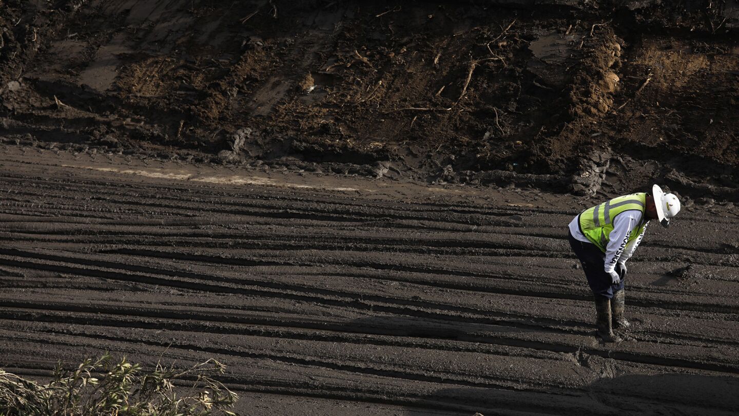 A worker takes a breather from directing a bulldozer driver who clears mud from the 101 freeway in Montecito.