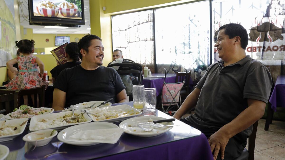 Fabian Nahui, right, owner of Intiraymi restaurant, chats with artist Eamon Ore-Giron.