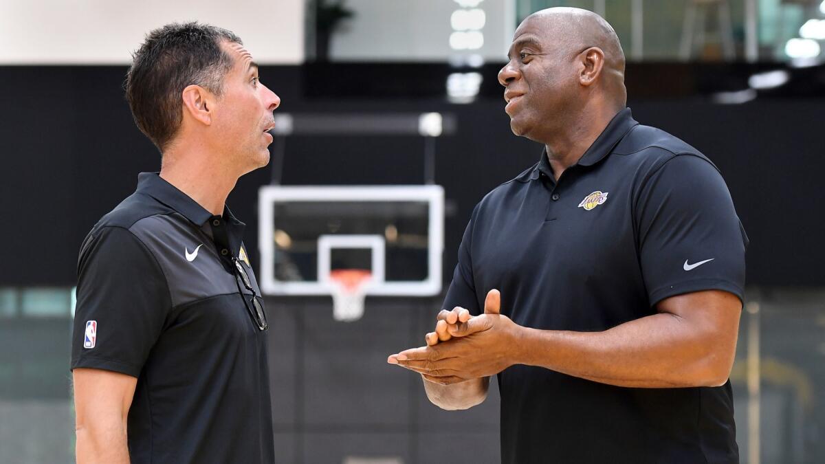 Lakers general manager Rob Pelinka, left, and Magic Johnson, president of basketball operations, chat before addressing the media on Thursday at their training facility in El Segundo.