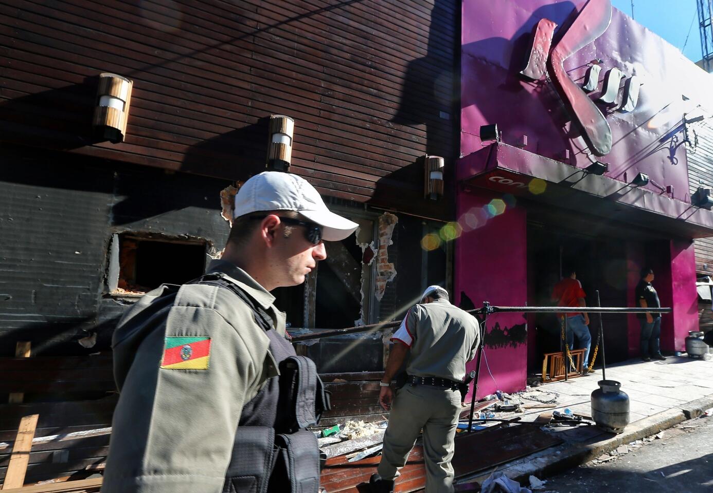 Policemen check the Kiss nightclub in Santa Maria, Brazil, where a blaze killed 235 people. Police have arrested four suspects -- two of the club's owners and two members of a band that staged a pyrotechnics show -- but some Brazilians say city officials are also culpable for allowing safety rules to be ignored.