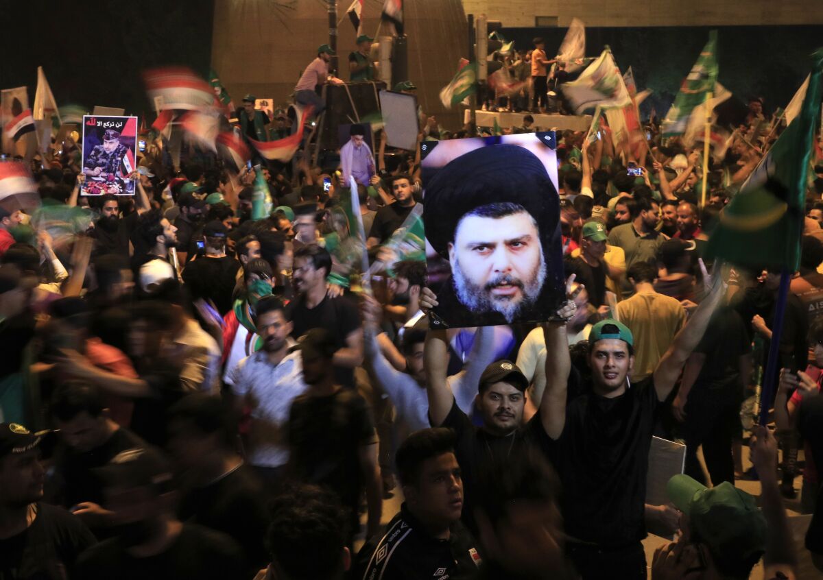 FILE - Followers of Shiite cleric Muqtada al-Sadr, on the poster, celebrate after the announcement of the results of the parliamentary elections in Tahrir Square, Baghdad, Iraq, Monday, Oct. 11, 2021. Eight months after national elections, Iraq still doesn't have a government. Driven by cutthroat competition for power and resources between elites, there is no clear way out of the unprecedented impasse. (AP Photo/Hadi Mizban, File)